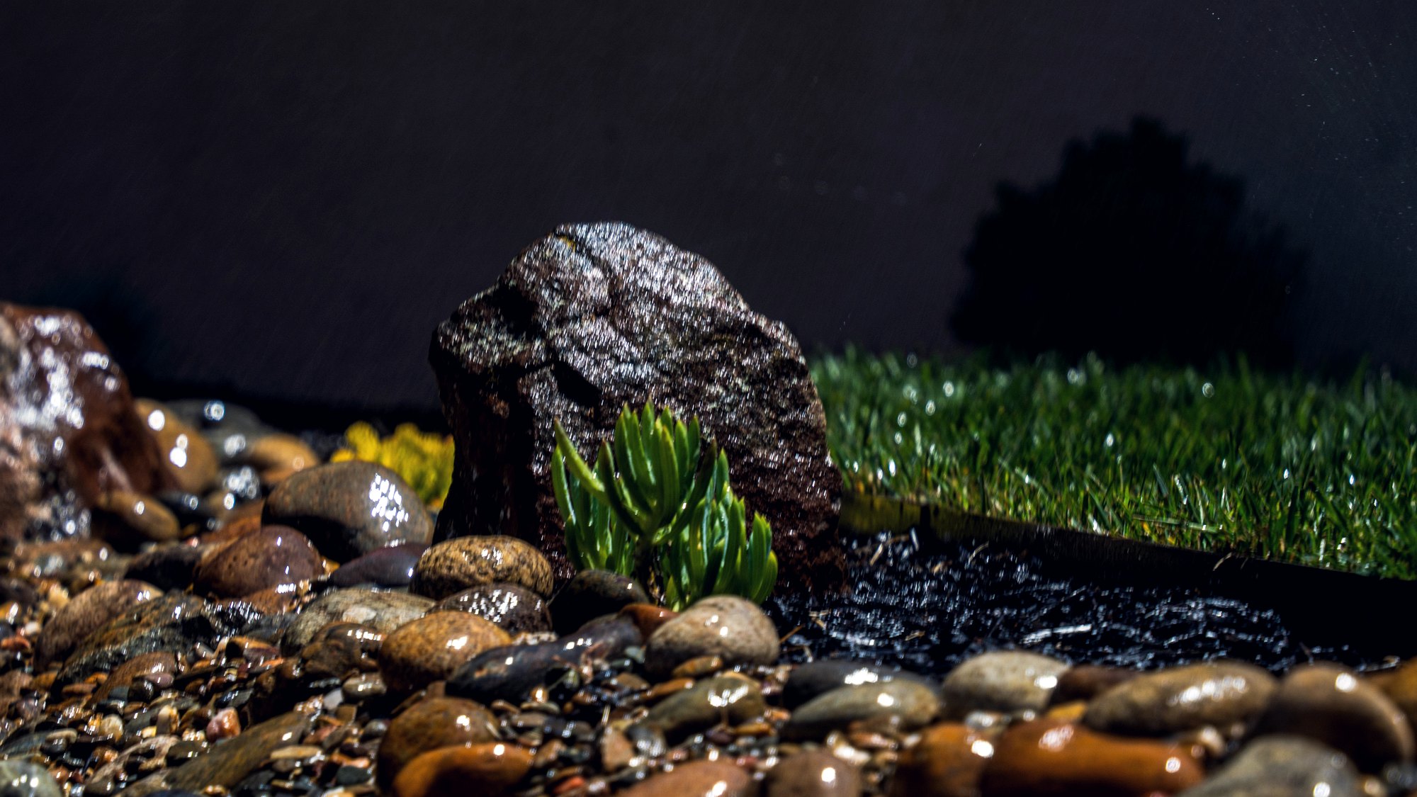 Close up of river rock, boulders and turf in a finished landscape bed